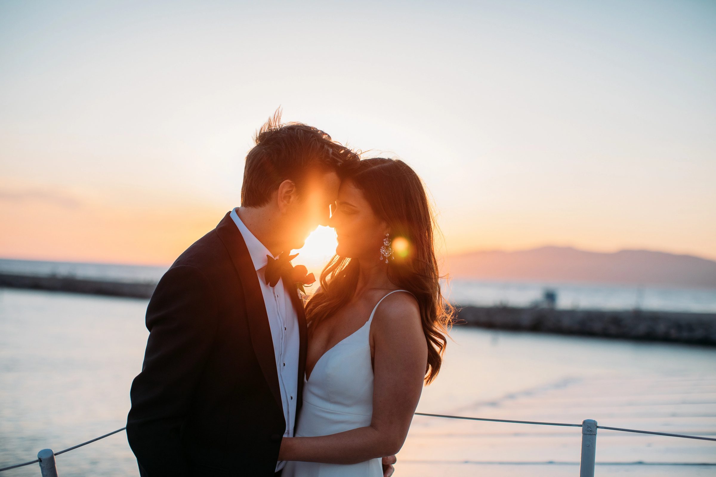 Bride and groom touch foreheads at sunset on the deck of a FantaSea yacht off Marina del Rey
