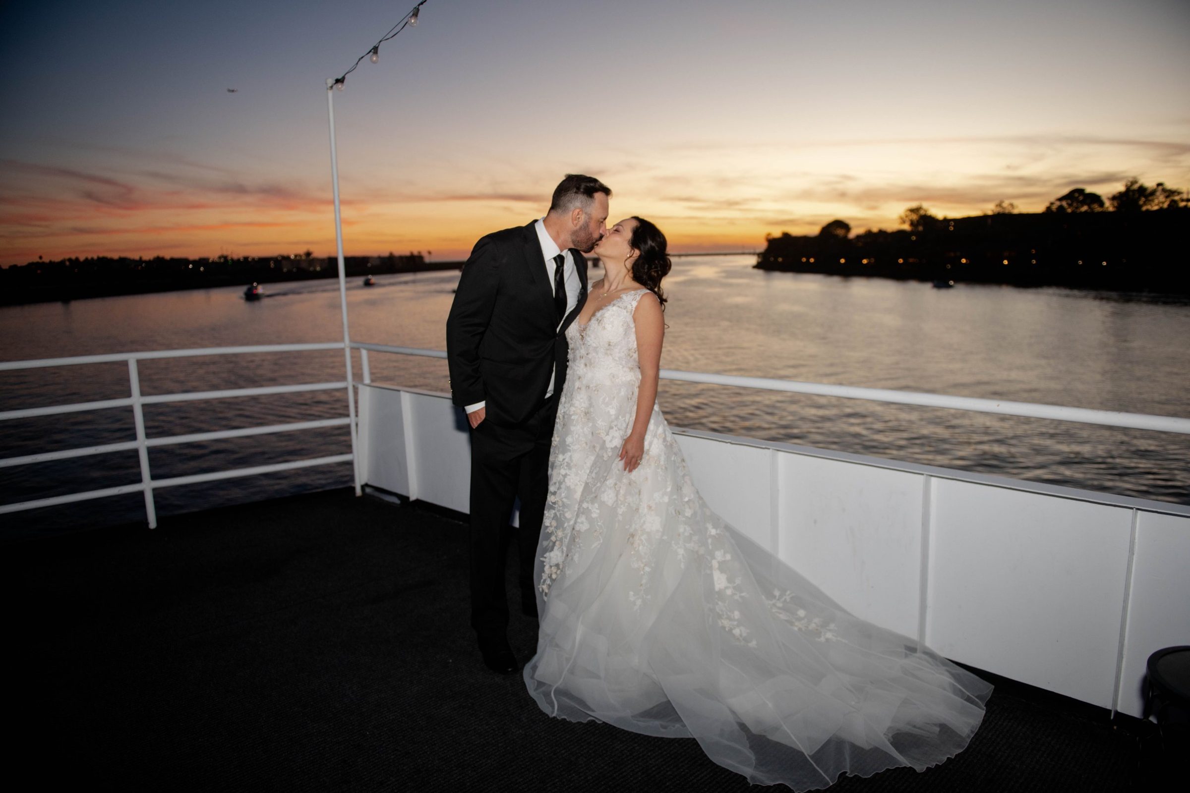 Bride and groom kiss at sunset on the deck of a FantaSea yacht in Marina del Rey